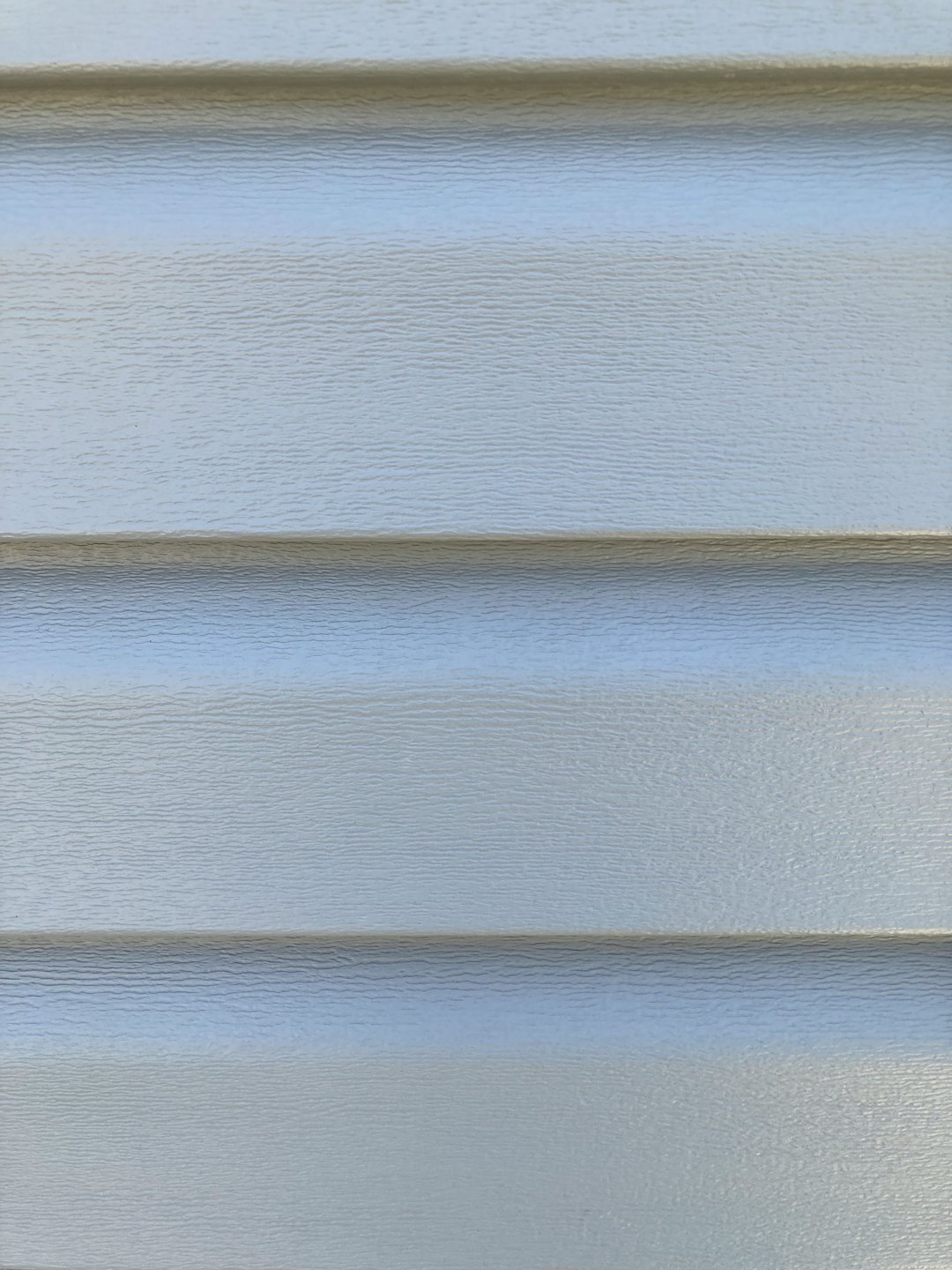 Light grey vinyl siding panels on a house exterior wall.